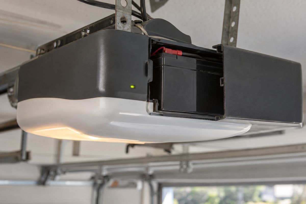 Garage door opener head unit with its cover open and a battery backup pack seated inside