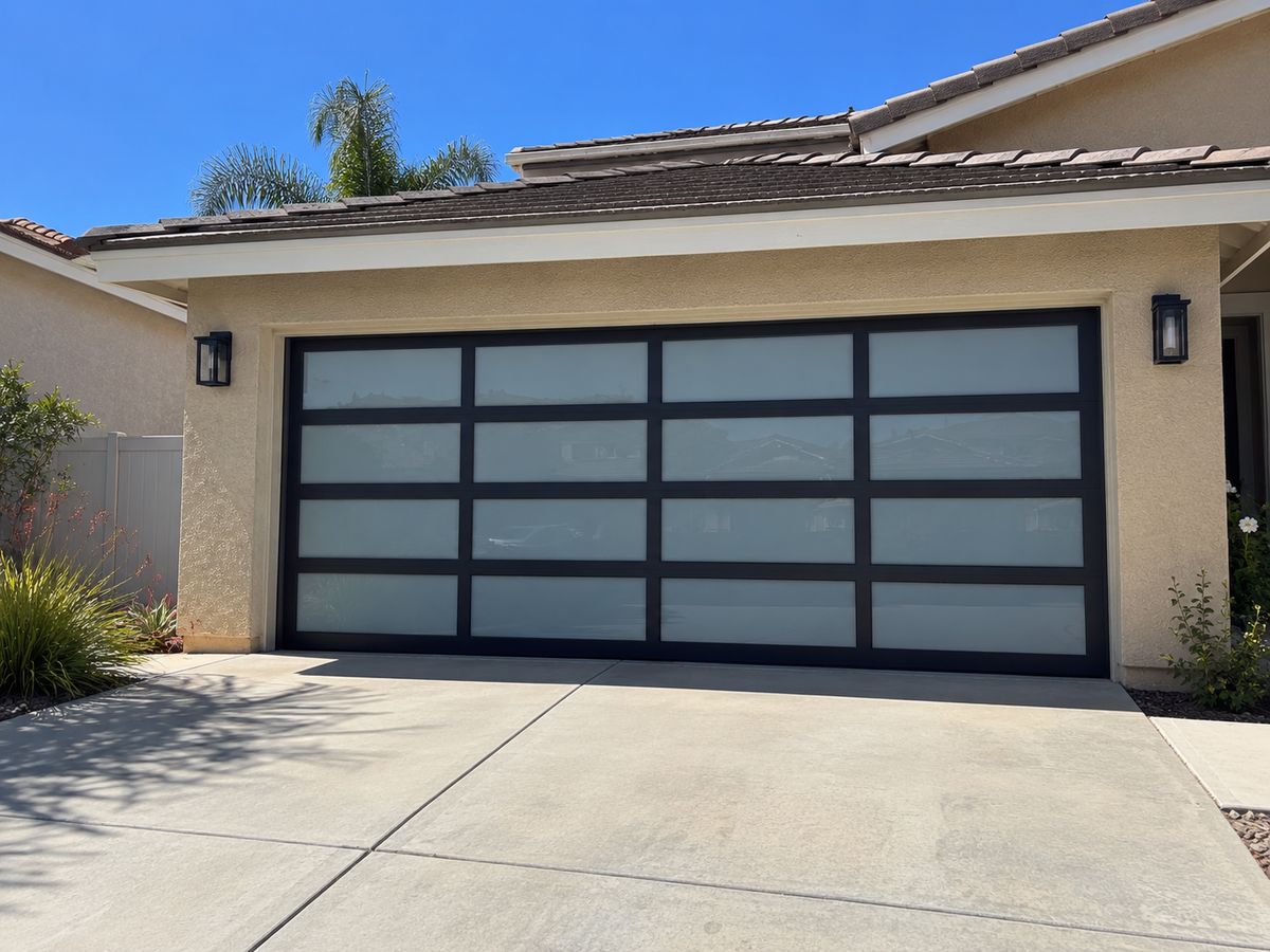 Full-view garage door with a black aluminum frame and frosted glass panels