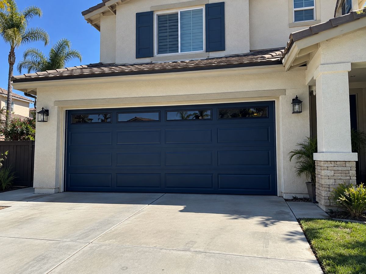 Navy blue garage door with a window row on a two-story home with matching navy shutters