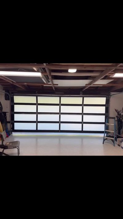 Full-view aluminum and frosted glass garage door opening, seen from inside an Anaheim garage with exposed beams