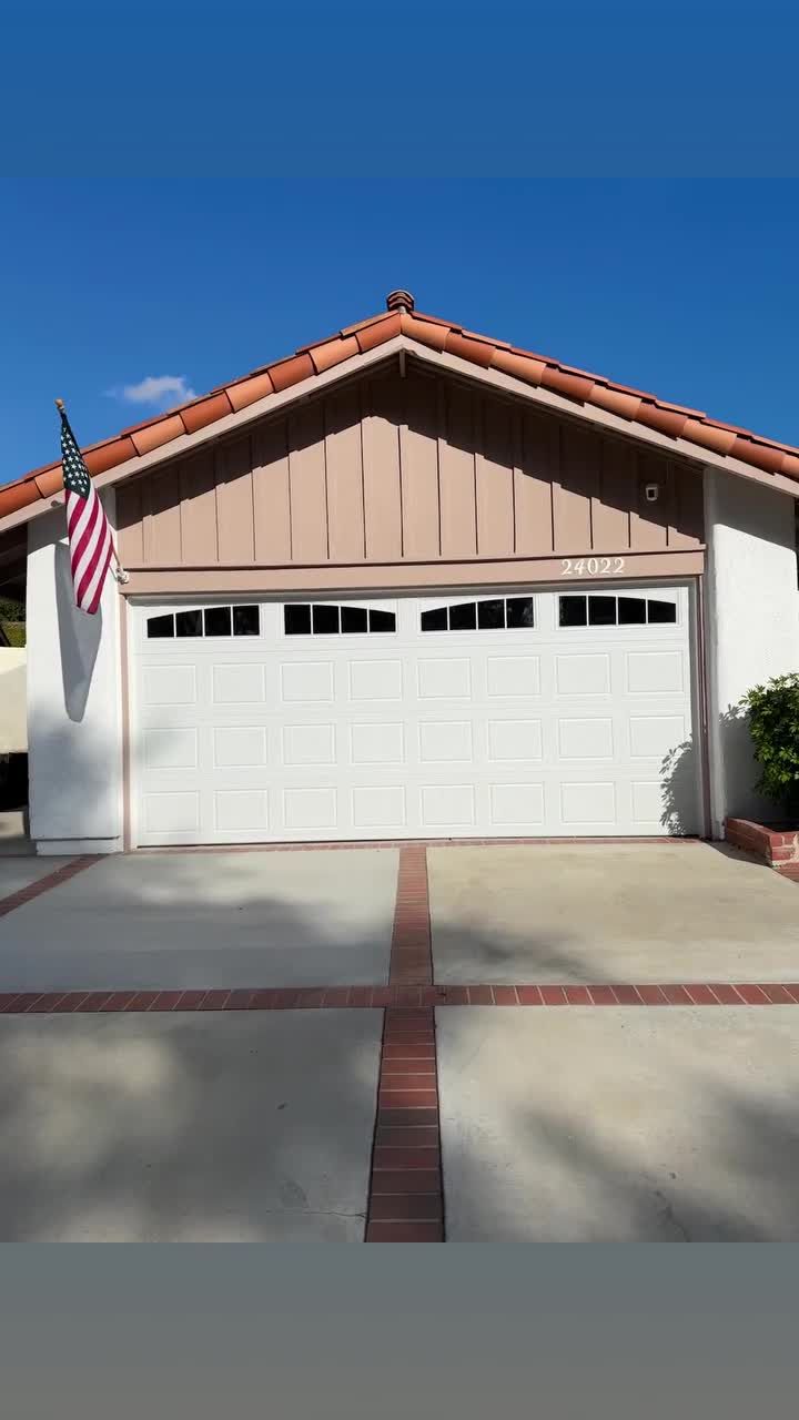 White raised-panel double garage door with a window row on a home with a red tile roof