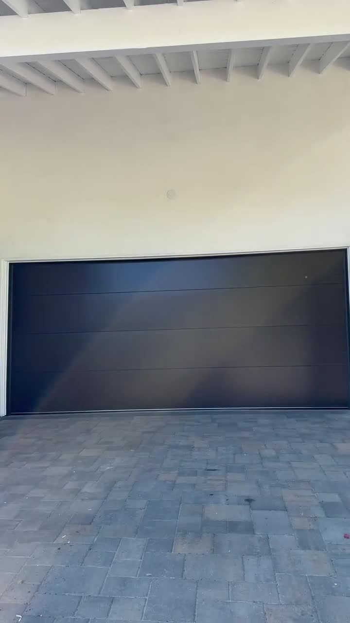 Before and after of a garage door replacement with a dark modern flush door on a white Los Angeles home