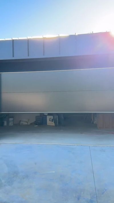 Light flush-panel modern garage door in Corona del Mar, Newport Beach, with the sun flaring over the top