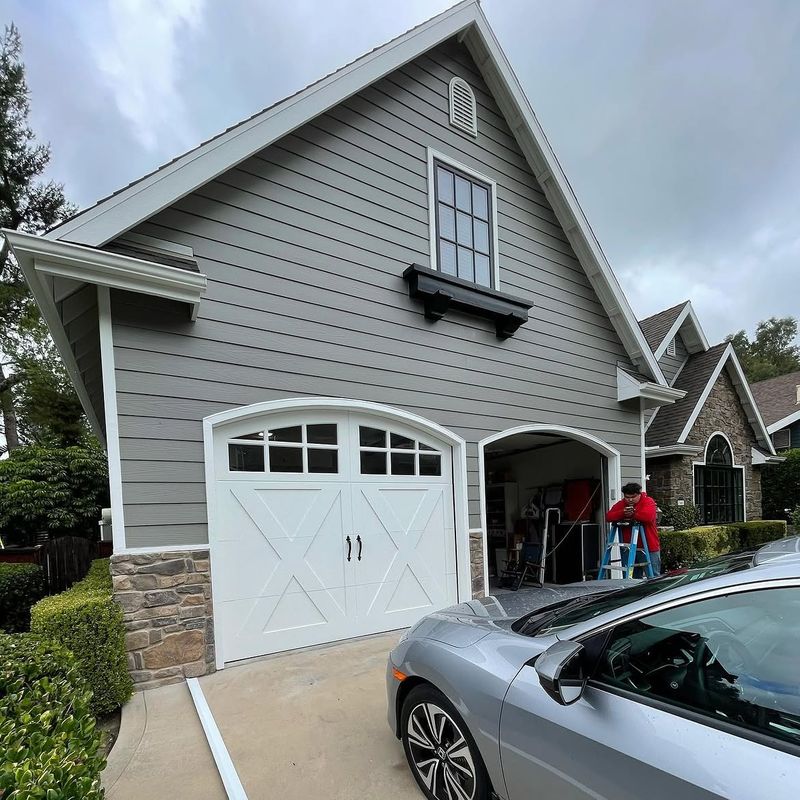 White carriage-house garage door with arched windows and cross-buck detail on a gray home in Coto de Caza