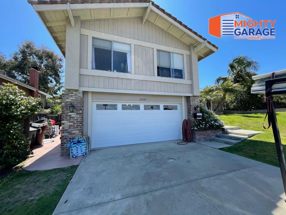 White raised-panel double garage door with a row of windows on a two-story Corona home with board-and-batten siding
