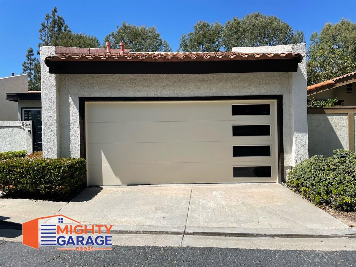 Cream flush-panel modern garage door with a vertical row of windows on an Irvine home with a tile roof